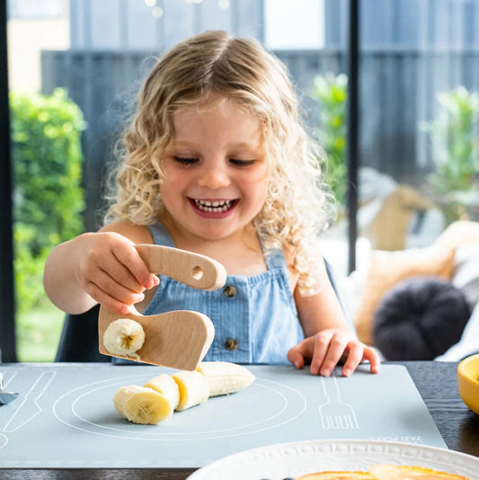 child chopping banana with zazi wooden knife